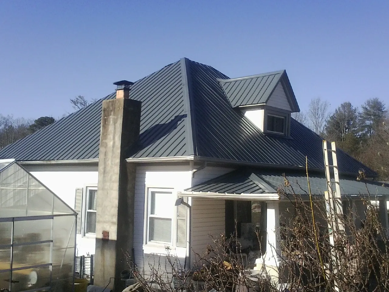 Dark blue standing seam metal roof on a white farmhouse with dormer — Slate & Tile Roof Repair by Roofing Brothers in Pilger