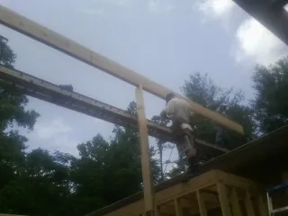 Carpenter setting a ridge beam over a new addition frame — Ice Dam Removal by Roofing Brothers in Pilger