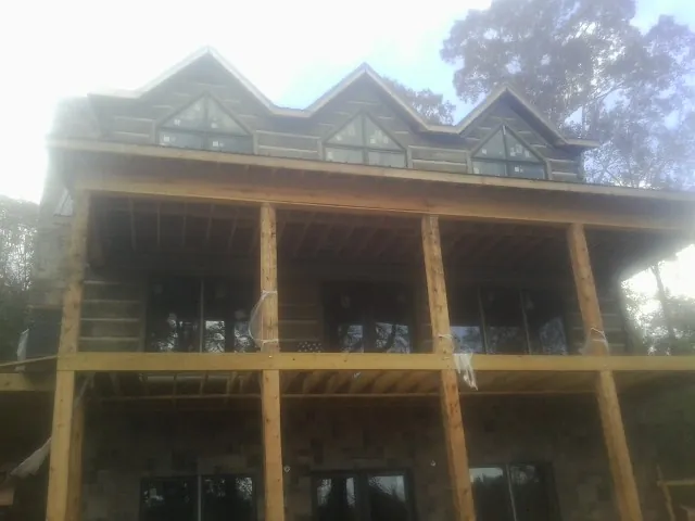 Dormers and porch framing on a large log home under construction — Roof Coating work by our crew in Pilger