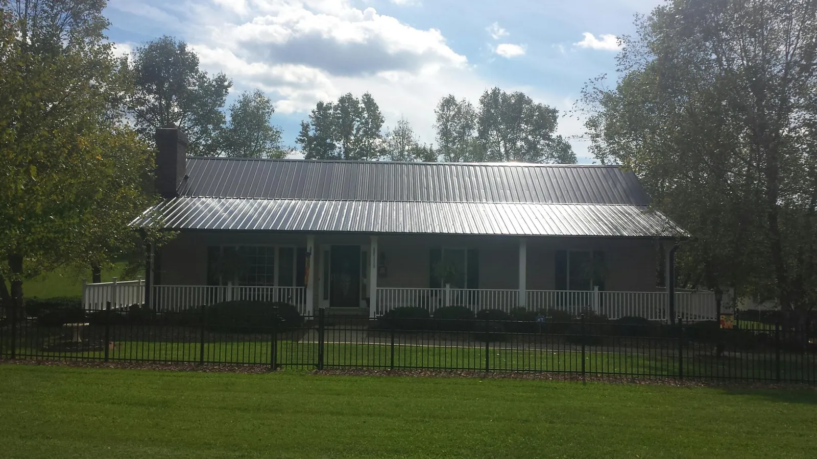 Gray metal roof on a brick ranch with a full width front porch — Gutter Guard Installation work by our crew in Pilger