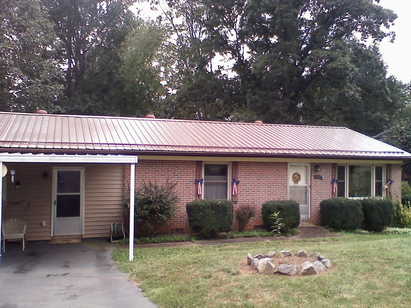 Bronze metal roof and carport on a brick ranch home — Roof Repair work by our crew in Pilger