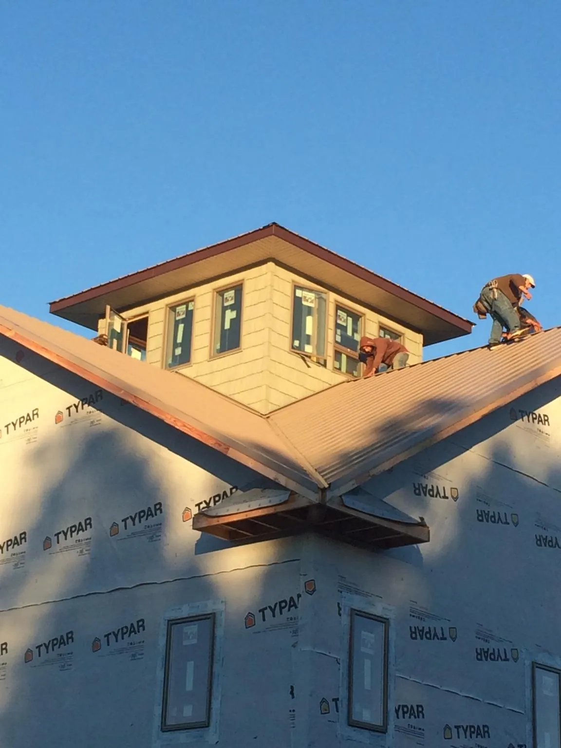Roofers working around a rooftop cupola on a new metal roof at sunset — Roof Waterproofing in Pilger by Roofing Brothers